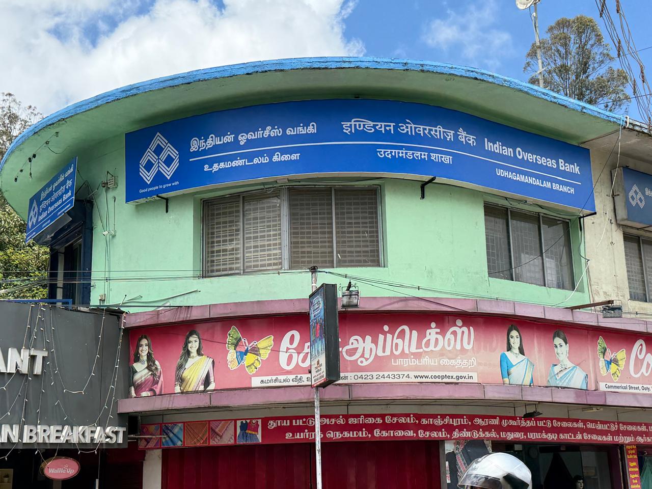 Indian Overseas Bank — Udhagamandalam branch · curved-building fascia, signage by Choice Advertising